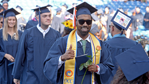 Student in graduation gown walking in commencement ceremony